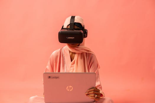 Woman wearing VR headset and using a laptop with a pink backdrop.